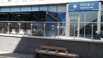 A restaurant with outdoor seating and a brick wall.