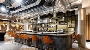 A modern bar area with a curved counter, multiple stools, and a well-stocked bar with bottles and glasses. - Novotel Leicester (Leicester)