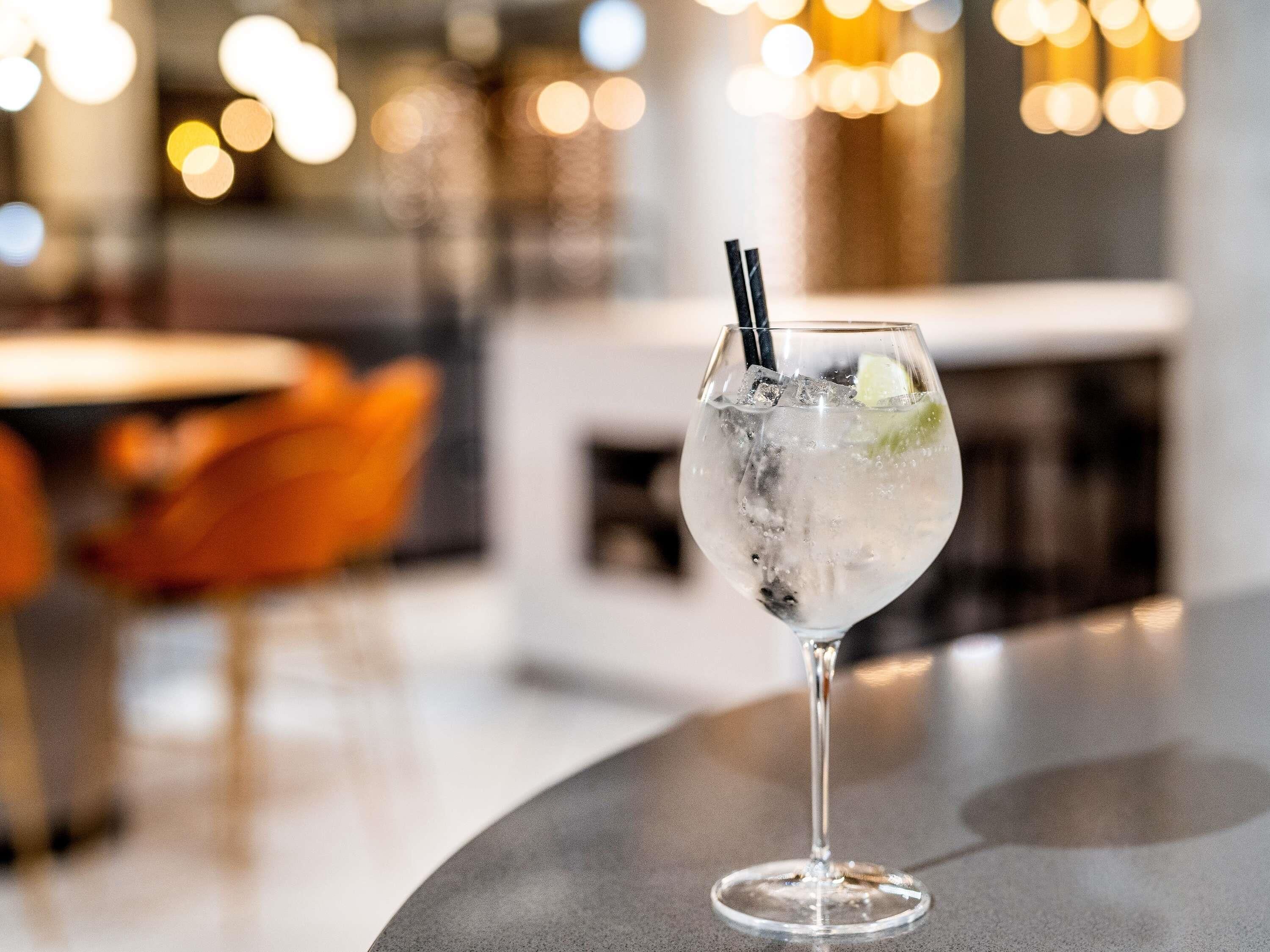 A glass with a straw and ice cubes on a bar counter.