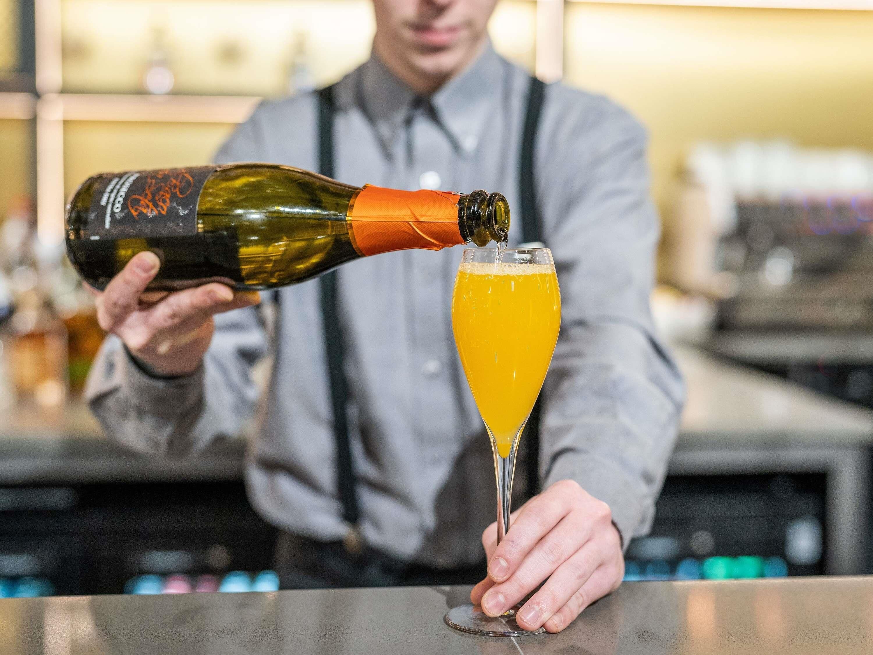 A person pouring a drink from a bottle into a glass.