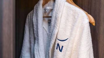 A white robe with a blue letter 'N' hanging on a wooden hanger.