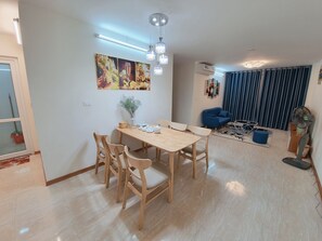 Cozy living area with a dining table for four, comfortable sofa, and a vase with greenery.