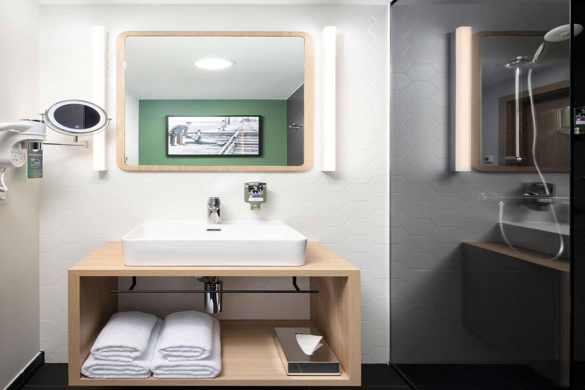 Une salle de bain moderne avec un meuble-lavabo en bois, un miroir, un lavabo et une douche.