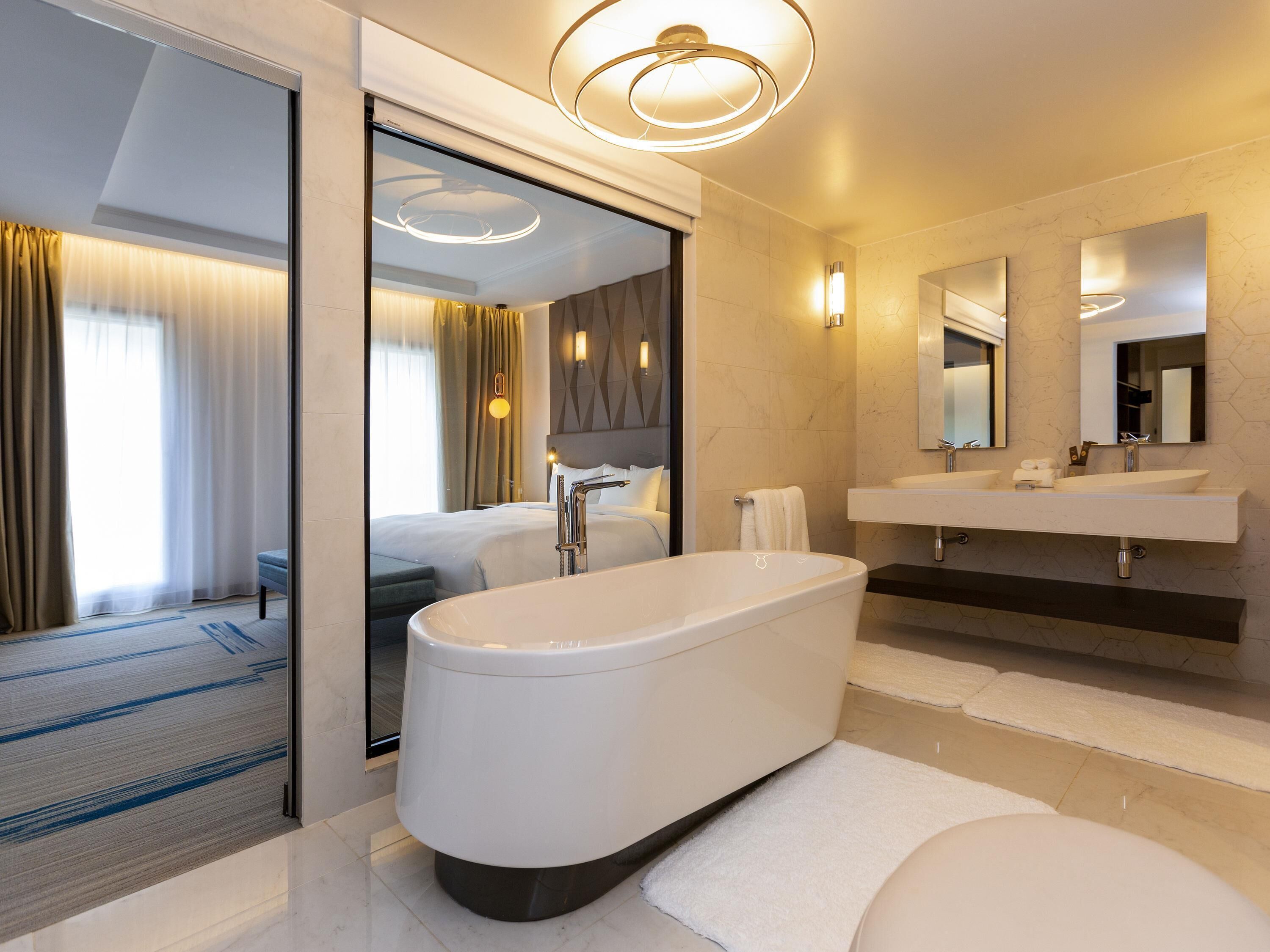 A modern bathroom with a freestanding bathtub, a large mirror, and a dual sink vanity.