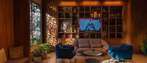 A modern living room with a large TV, wooden shelves, and comfortable seating.
