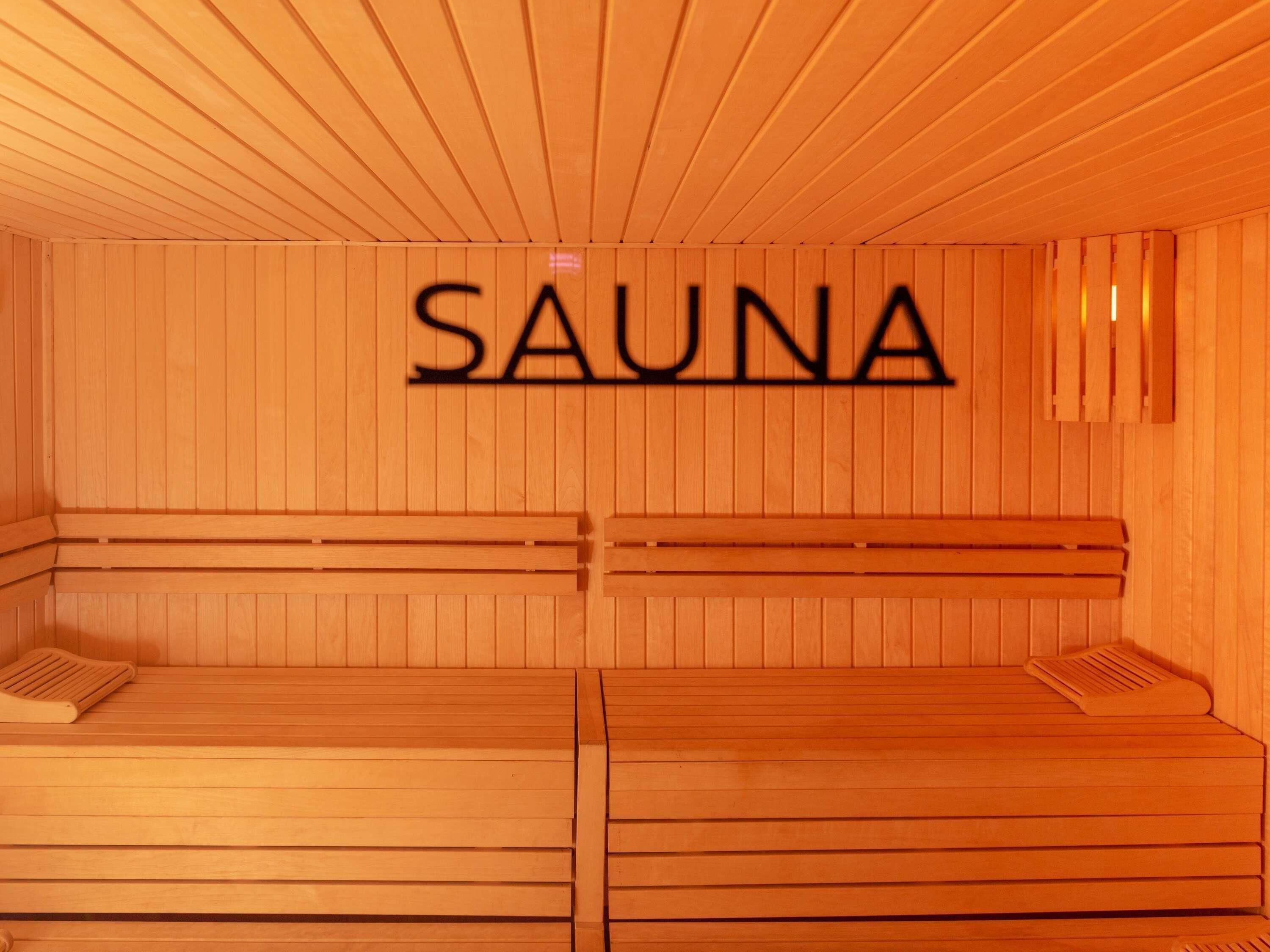 A sauna room with wooden benches and a 'SAUNA' sign on the wall.