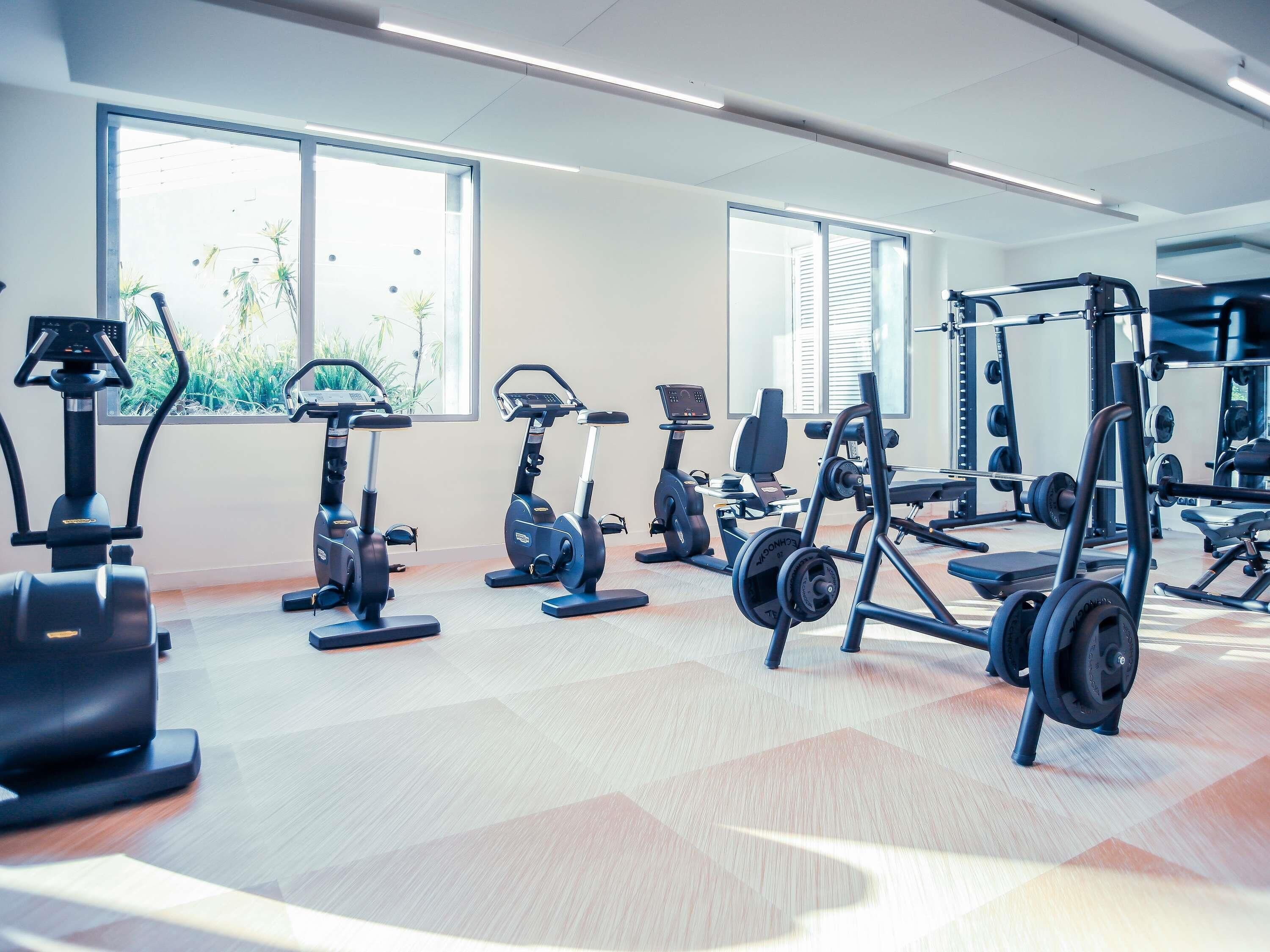 A gym with cardio machines, weightlifting equipment, and large windows.