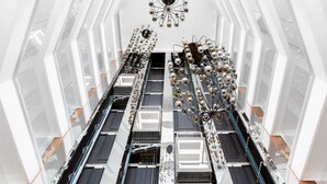 A modern interior with a central walkway, geometric ceiling design, and hanging light fixtures. - Novotel Convention And Spa (Antananarivo)