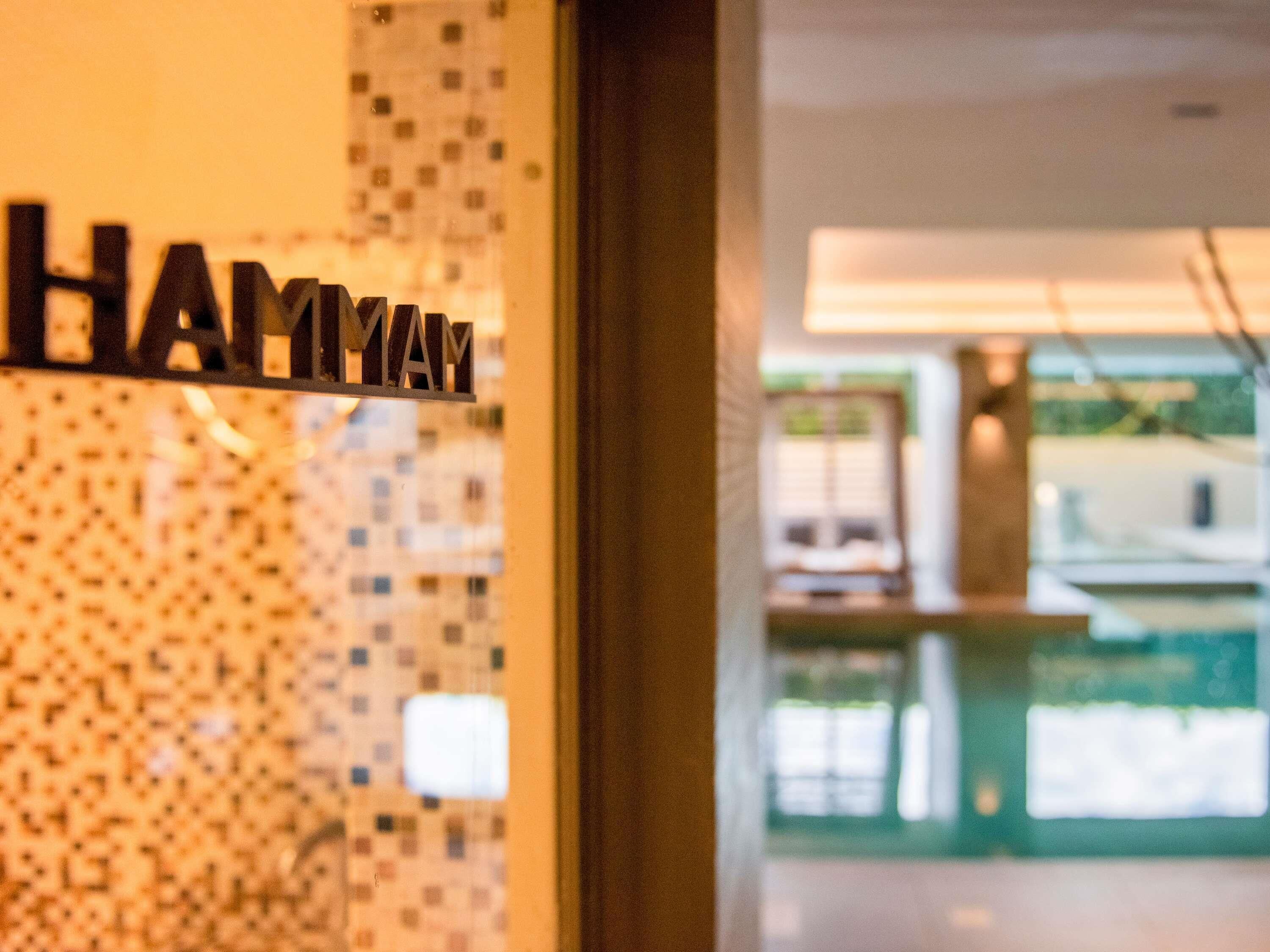 A hotel sign with the name 'HAMYAM' and a view of a pool area.