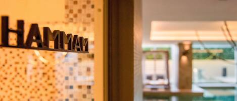 A hotel sign with the name 'HAMYAM' and a view of a pool area.