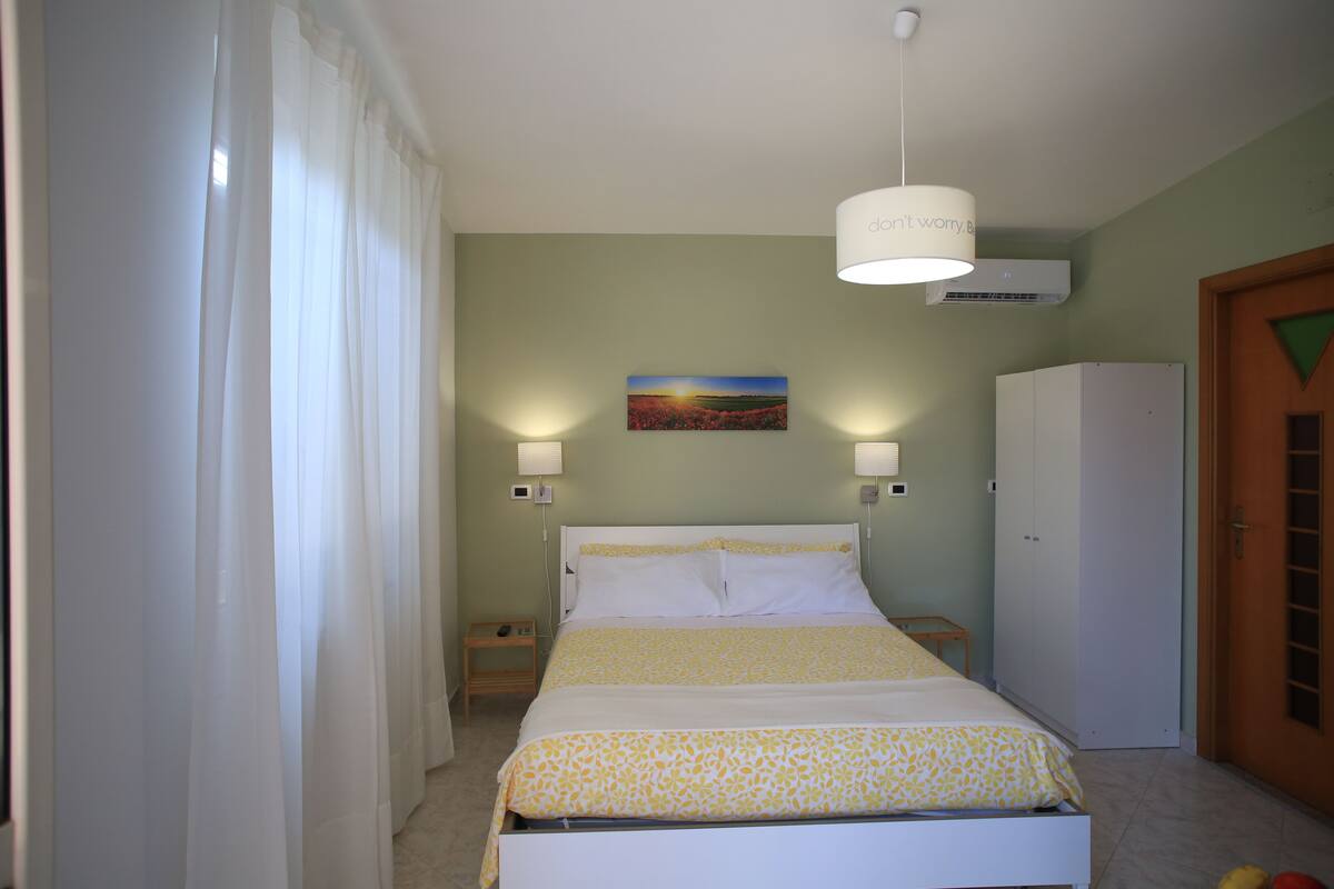 A bedroom with a bed, a nightstand, a wardrobe, and a painting on the wall.