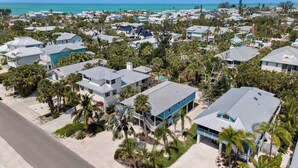 Zona residencial costera con casas, palmeras y una playa al fondo.