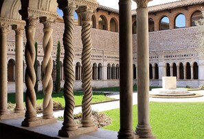 Un patio con columnas y arcos, una fuente y un edificio con intrincados detalles de piedra.