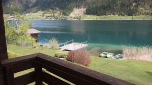 A lakeside view with a dock, boats, and houses in the background. - Chalets Zöhrer - Wohnen am Wasser (Weissensee)