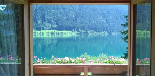 A view of a lake surrounded by forest, with a wooden deck in the foreground.