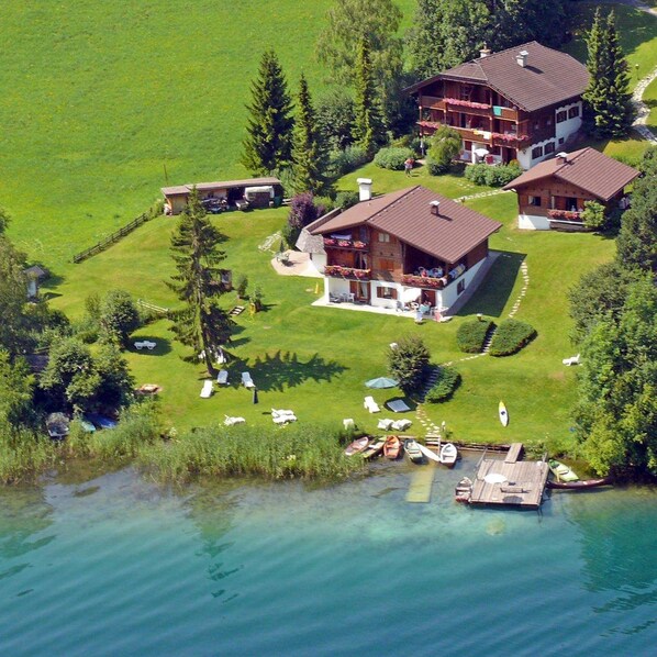 A large house with a balcony, surrounded by a well-maintained lawn and a dock with boats.