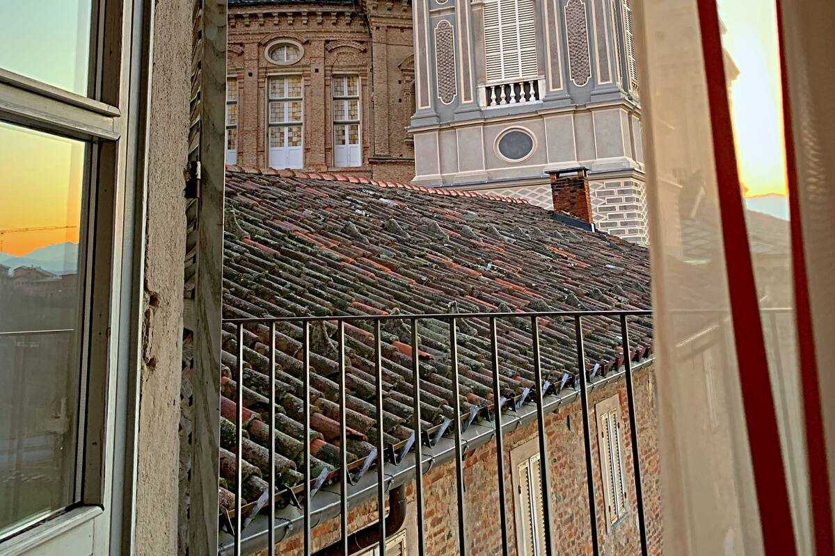 A view of a historic building with a clock tower and a dome, viewed from a balcony with a metal railing.