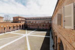 A courtyard with a central open space, surrounded by buildings with arched windows and doors. - Casa Regina Montis Regalis (Vicoforte)