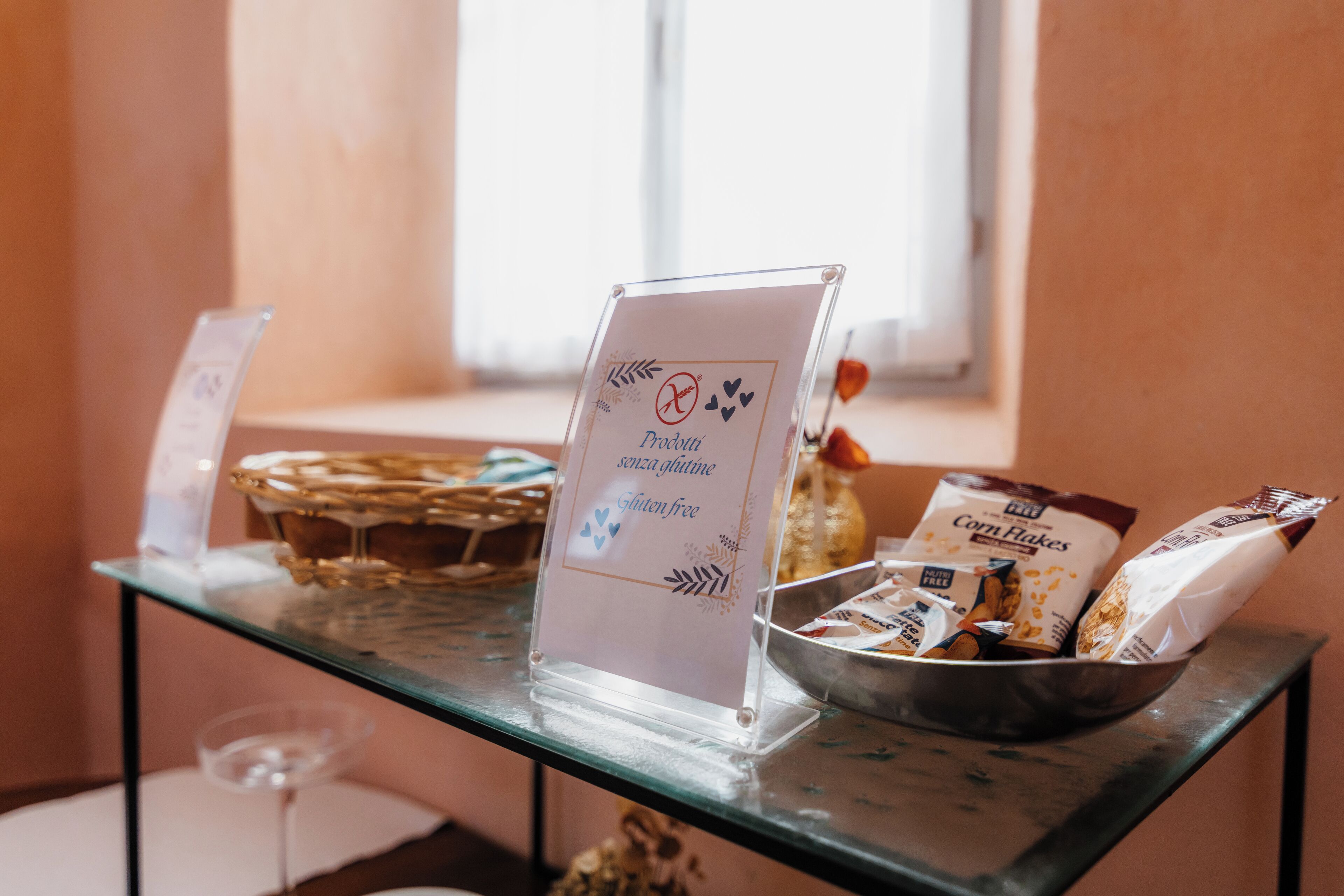 Un tavolo per il buffet con un cartello che indica opzioni senza glutine, una ciotola di fiocchi di mais e un bicchiere di vino.