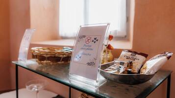 Un tavolo per il buffet con un cartello che indica opzioni senza glutine, una ciotola di fiocchi di mais e un bicchiere di vino.