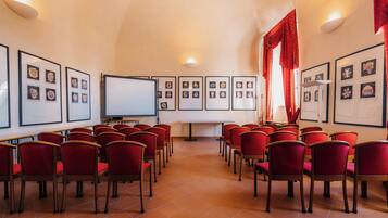 A conference room with red chairs arranged in rows, a whiteboard, and framed pictures on the walls.