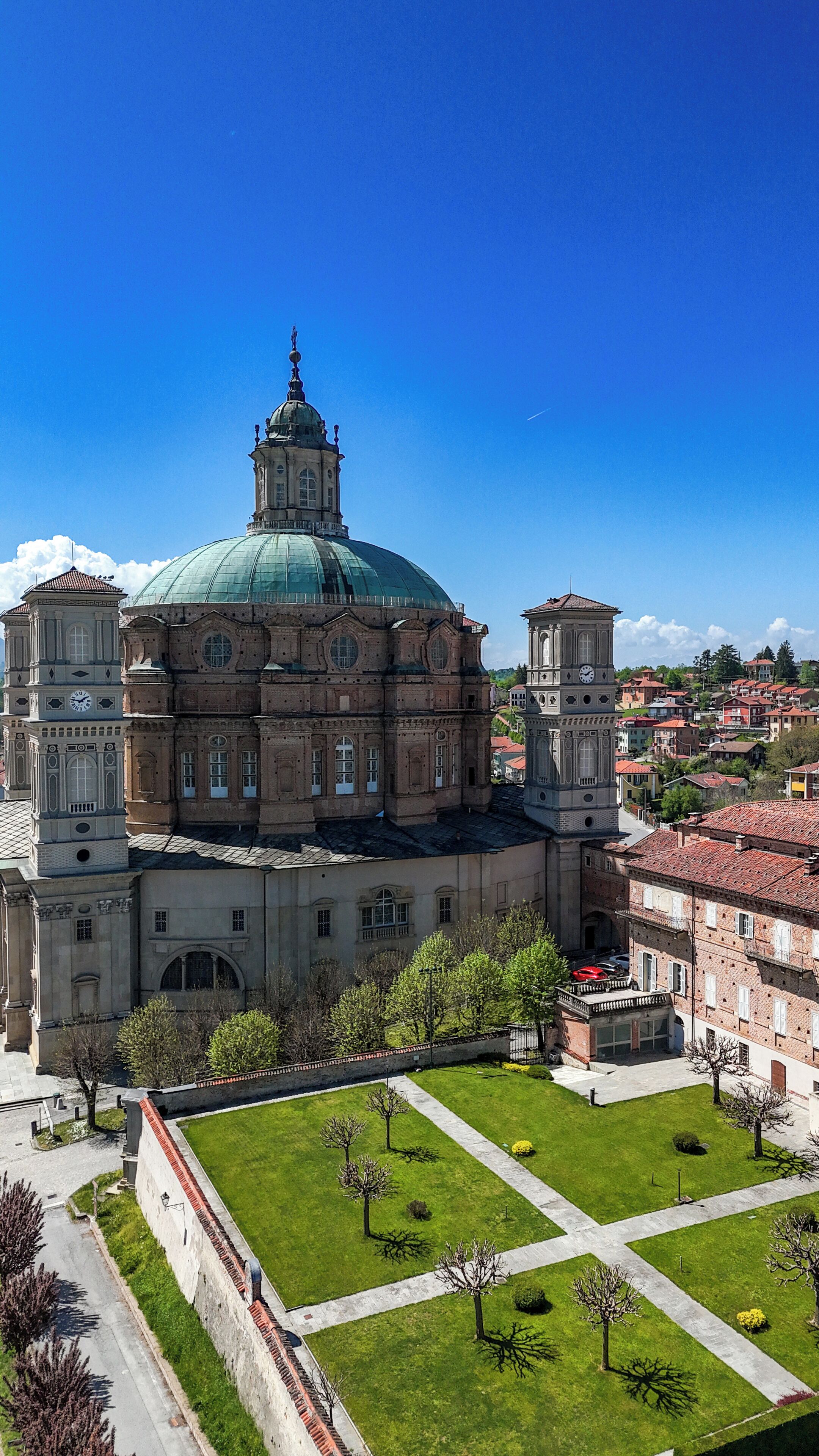 A large historic building with a prominent dome and clock tower, surrounded by a well-maintained courtyard.