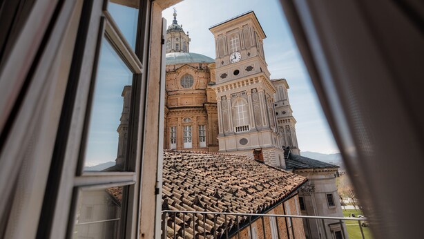 Une vue à travers la fenêtre d’un bâtiment doté d’un toit en tuiles et d’un clocher.