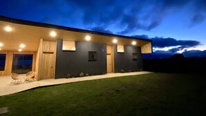 A modern house with a covered patio, large windows, and a well-lit exterior at dusk. - The Line Hotel (Natales)
