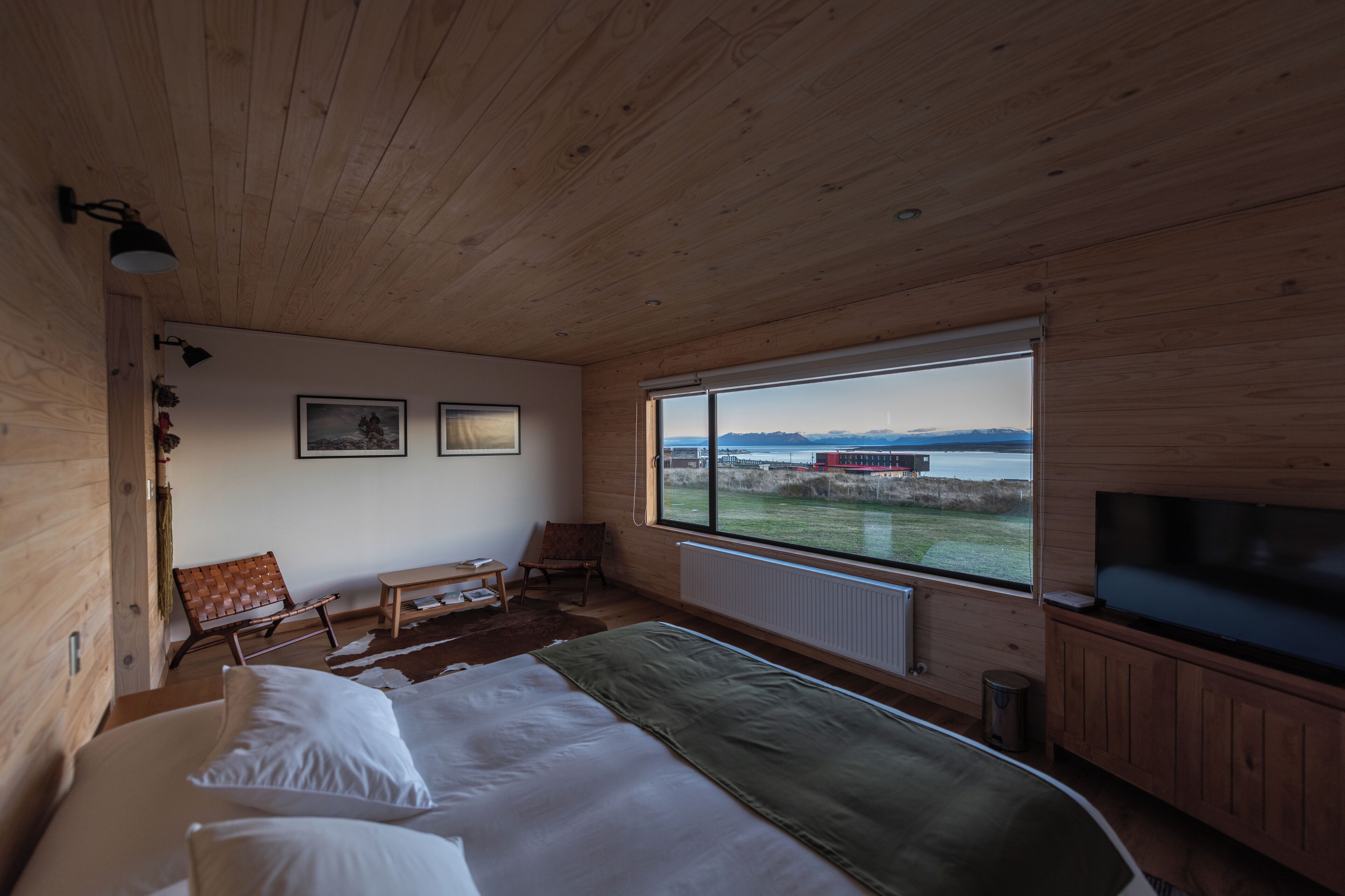 Ein Schlafzimmer mit großem Fenster, Holzboden und einem Bett.