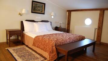 A bedroom with a bed, bedside tables, a nightstand, a bench, a rug, and a wall-mounted lamp.