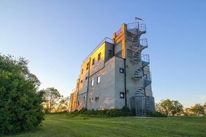 Un edificio de varios pisos con una escalera de incendios y un área verde en la parte delantera.