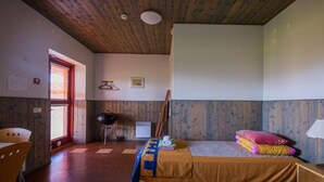 A room with a bed, a chair, a table, and a window.