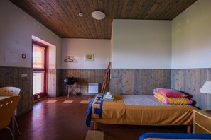 A room with a bed, a chair, a table, and a window.
