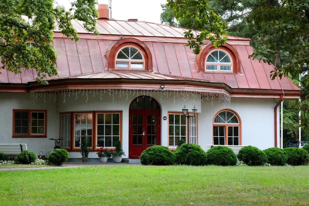 Une maison à deux étages avec une porte rouge, des fenêtres en arc de cercle et un toit en métal.