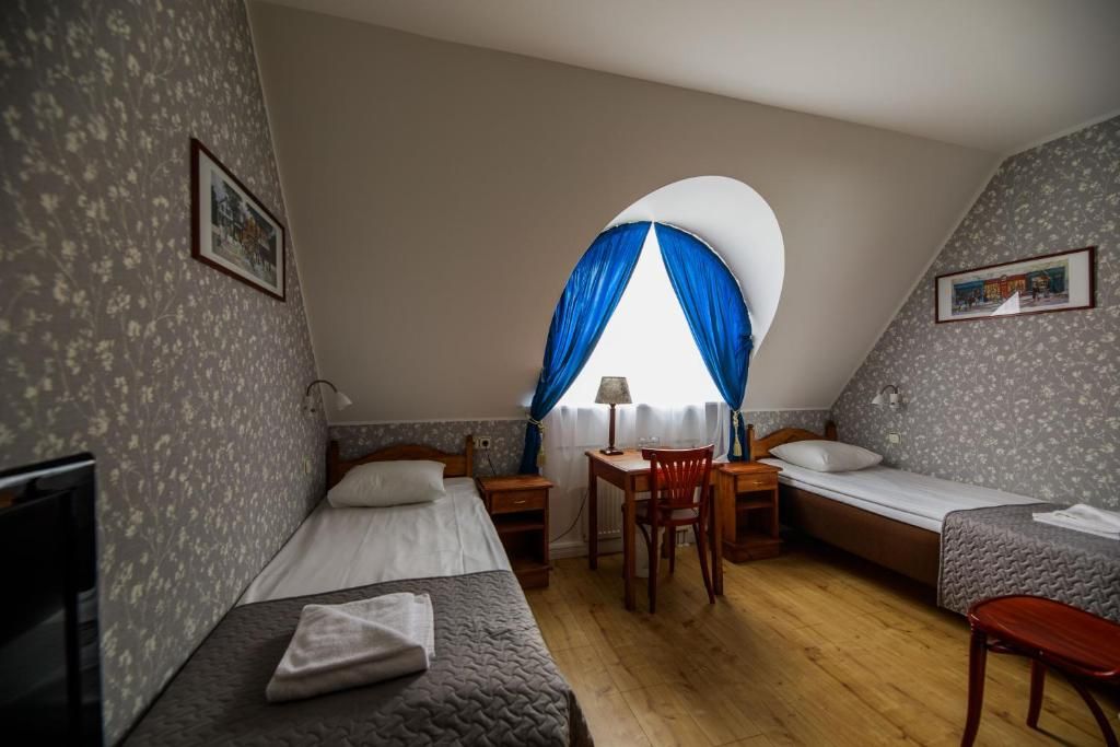 A room with two single beds, a desk with a chair, and a small table.