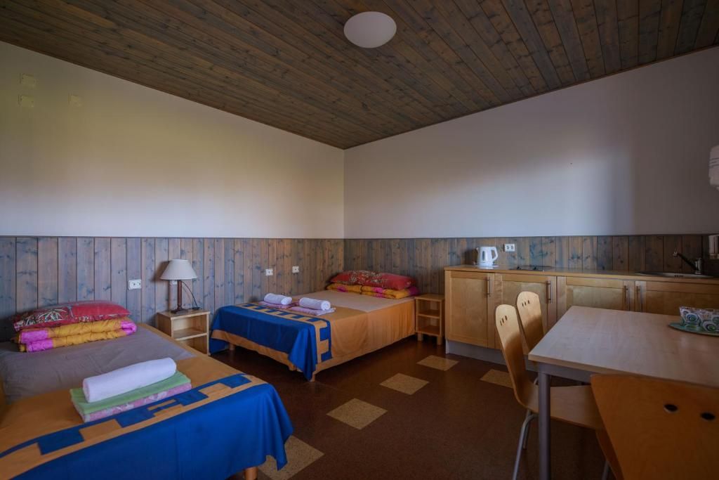 A room with two beds, a small kitchenette, and a dining table.