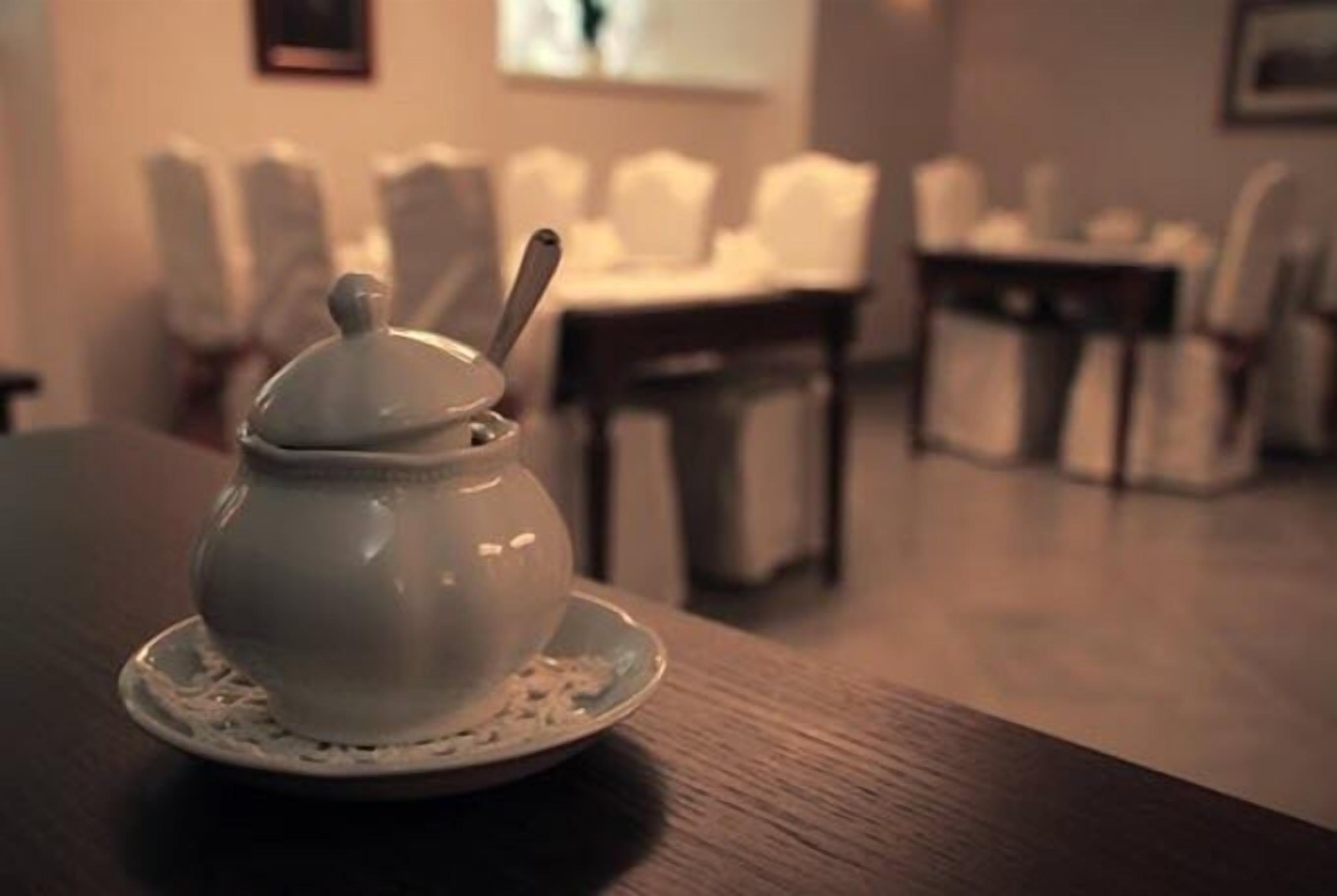 Een witte keramieken theepot op een tafel met een bijpassend schoteltje.