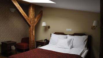 A hotel room with a bed, a chair, a nightstand, and a lamp.