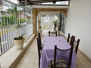 A covered patio with a table and chairs, a stone wall, and a view of the street. - Hotel Terrazas Boutique (San Pedro)