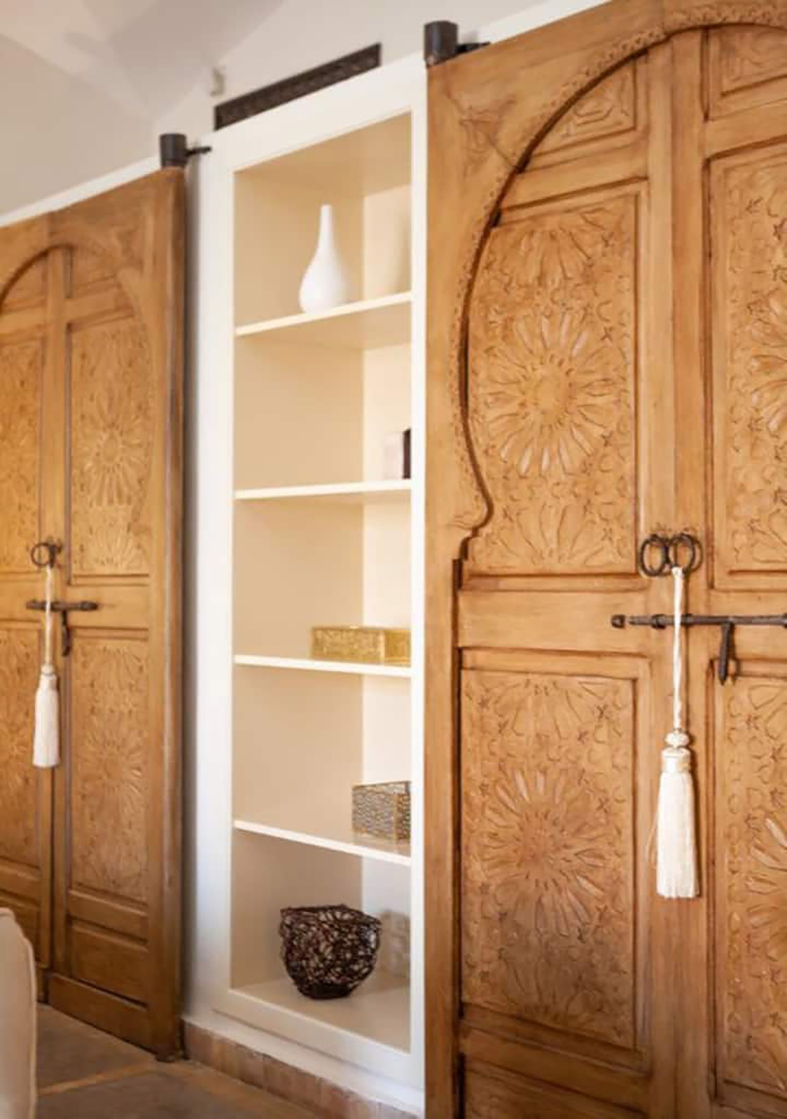 A wooden door with intricate carvings and a white shelf with decorative items.