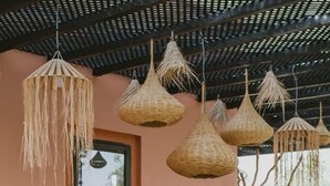 Un espace extérieur aménagé pour les repas, avec des meubles en osier et des luminaires suspendus.