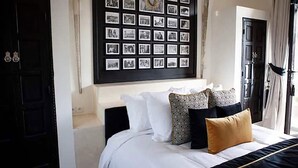 Une chambre à coucher avec un lit, des oreillers, un collage de photos accroché au mur et une porte.