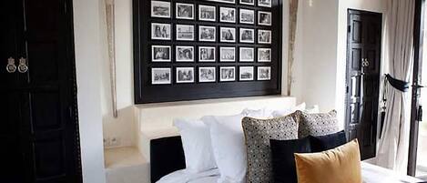 A bedroom with a bed, pillows, a wall-mounted photo collage, and a door.