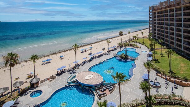 Un complexe hôtelier doté de plusieurs piscines, d’une plage et d’un grand bâtiment.