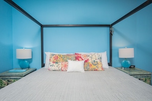 A room with a four-poster bed, two bedside tables with lamps, and a blue wall. - Sonoran Sun E-707 Happy-N-The-Sun  2 BR Oceanfront (Puerto Peñasco)