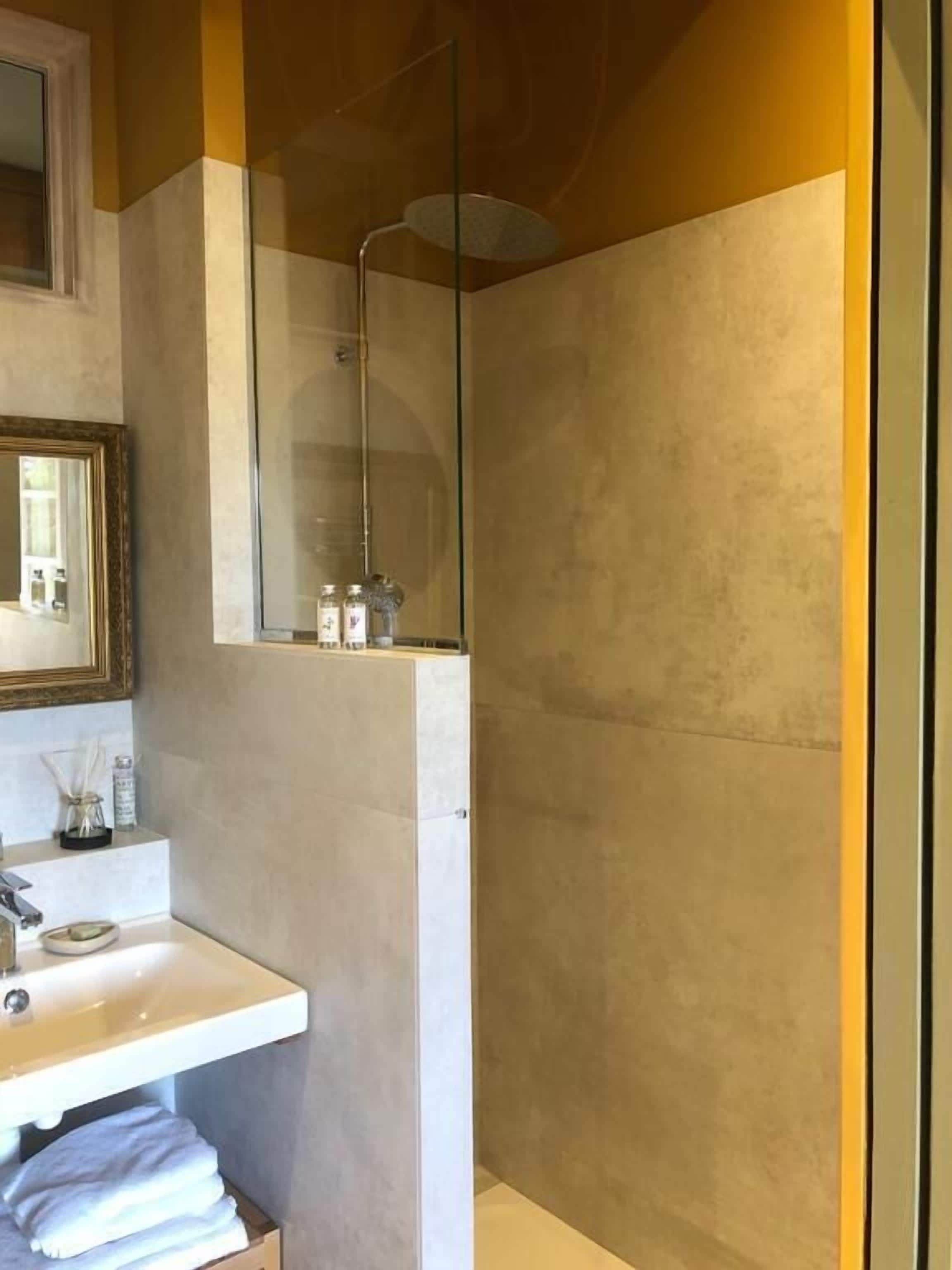 Une salle de bain moderne avec un lavabo blanc, un miroir et un espace douche.