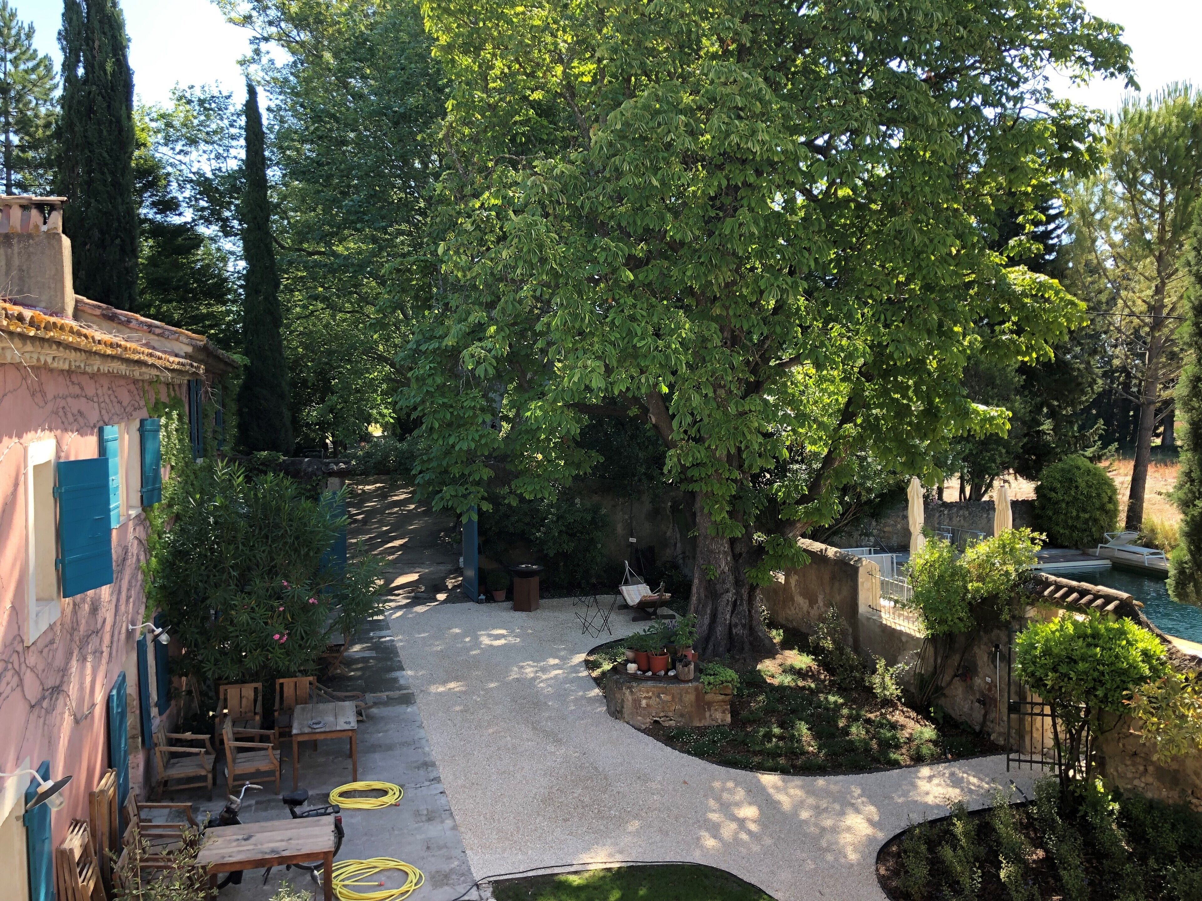 Une cour avec un chemin de gravier, des meubles en bois et des plantes en pot.
