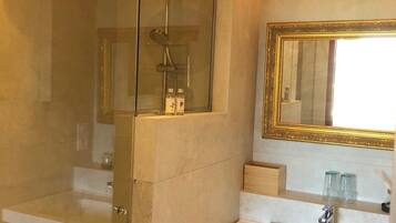 A modern bathroom with a glass-enclosed shower, a white sink, and a mirror with a gold frame.