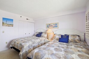 Une chambre avec deux lits, une table de chevet, une lampe et des œuvres d’art accrochées aux murs.
