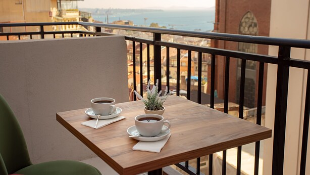 A balcony with a wooden table, two cups of coffee, and a small potted plant. - West Palace Hotel (Istanbul)